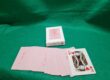 Custom wedding playing cards with monogram "E H" and date "6.6.2026" on a white tuck box, displayed with the full deck fanned out showing a blush pink custom card back design, on a green felt surface. Printed by The Playing Card Factory.