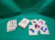 Custom playing card deck titled "The Things We Love – Cat Edition" displayed on a green felt surface, showing the tuck box and five face-up cards featuring illustrated black-and-white cat artwork on cream-coloured card stock.